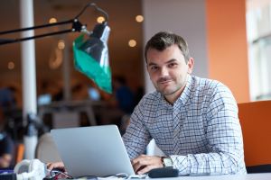 Uśmiechnięty mężczyzna pracujący przy komputerze