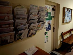 Drzwi wejściowe ZUS. Na ścianach wiszą organizery, w których znajdują się wnioski, świadczenia i ulotki informacyjne.