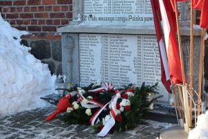 Złożone kwiaty i znicze pod Tablicą Towarszystwa Gimnastycznego "Sokół"