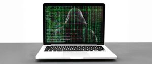 Laptop, na którego pulpicie jest postać hakera i metadane komputera