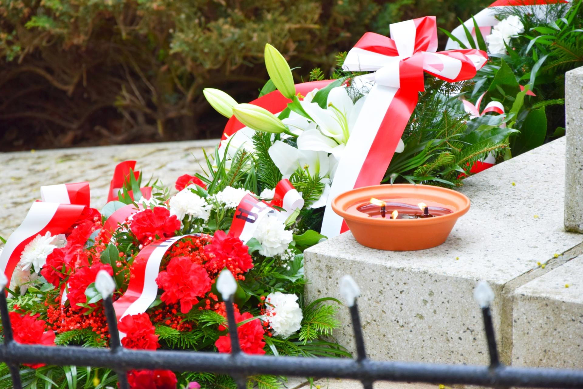Kwiaty i znicz złożone przy pomniku na cmentarzu wojennym w Książkach